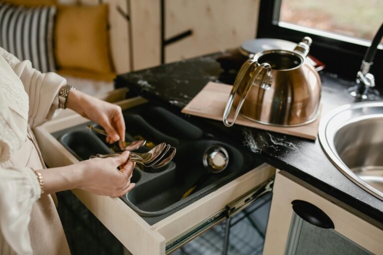 A person efficiently organizes silverware in a minimalist kitchen setting over a drawer dividers